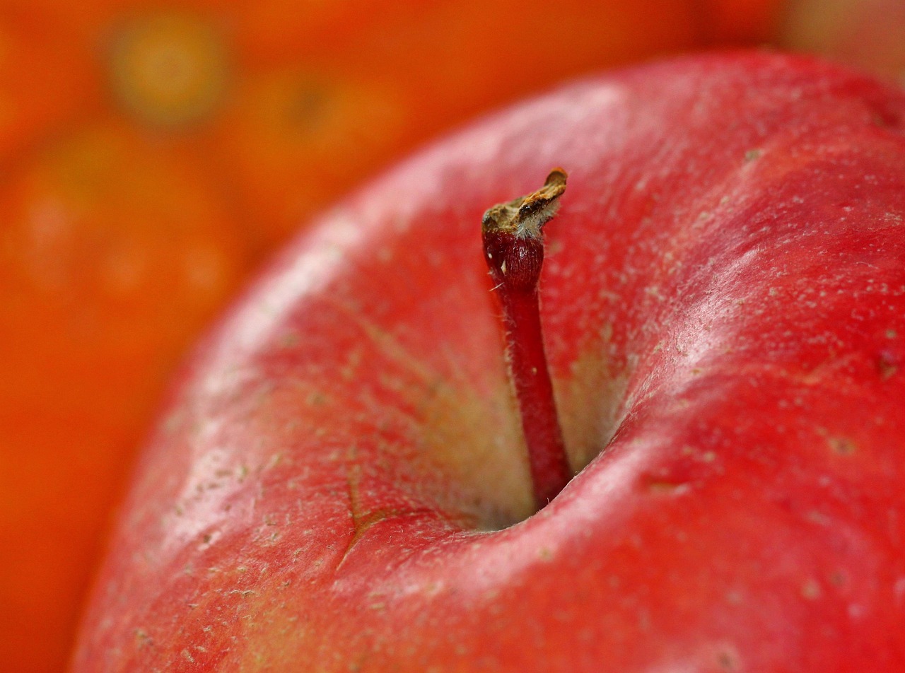 A fresh green apple placed next to a highly processed glazed donut