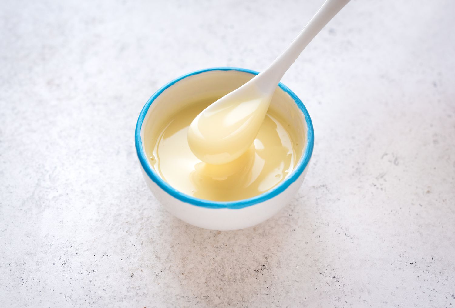 Creamy white condensed milk in a ceramic bowl with a blue rim.