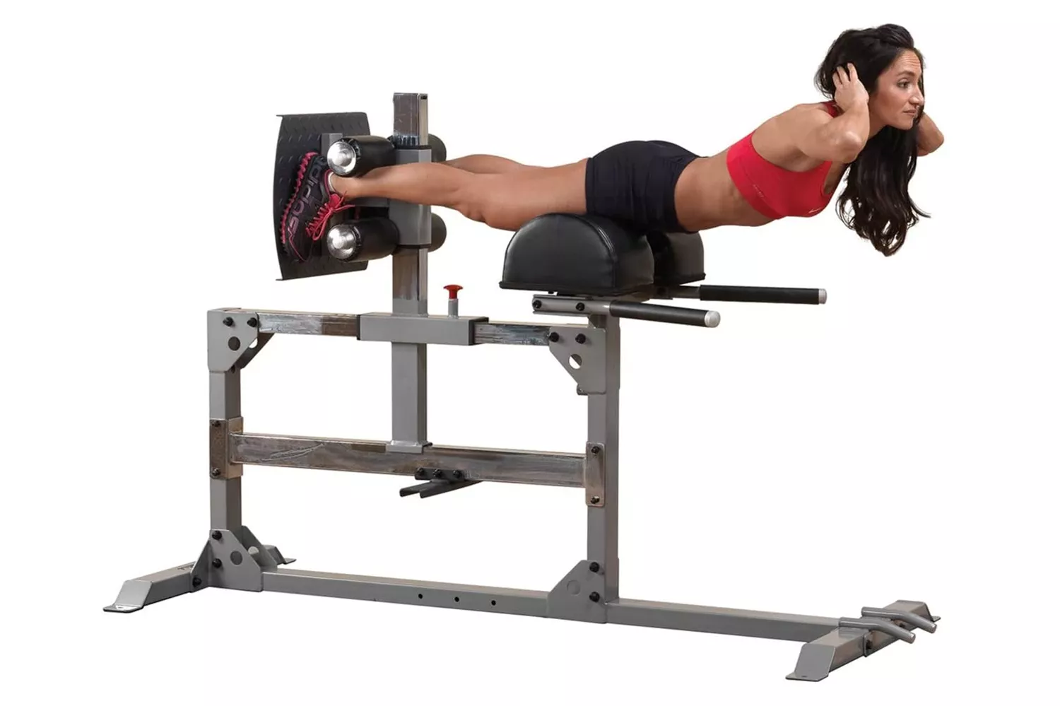 A woman performing a hyperextension exercise on a glute and hamstring machine, showing proper torso elevation and leg positioning.