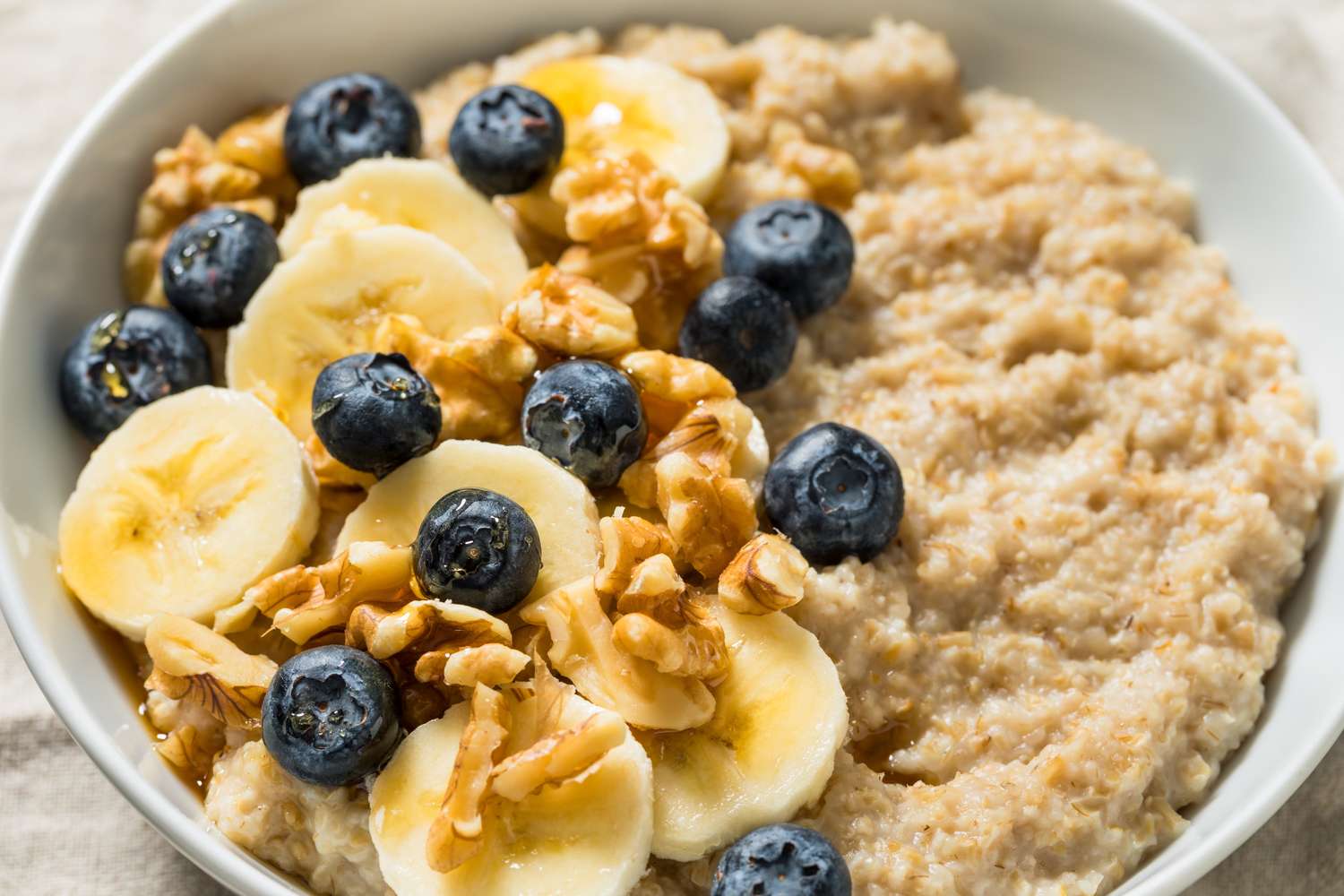 A bowl of steel-cut oatmeal topped with fresh fruit and walnuts.