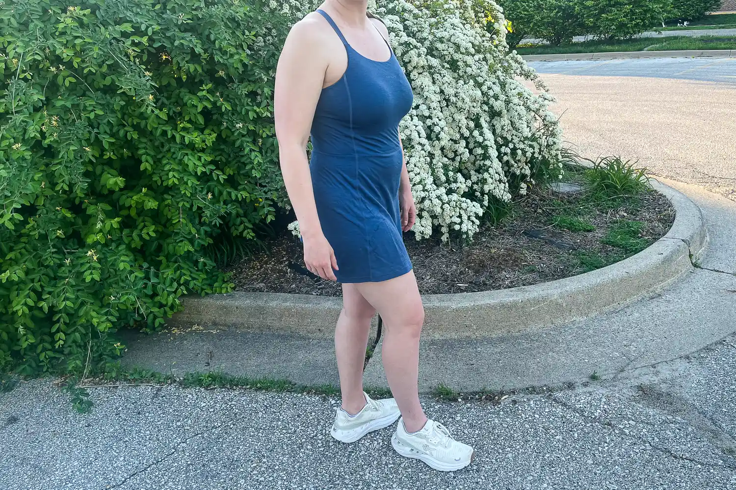 A woman in a blue athletic dress walking on a path in a park.
