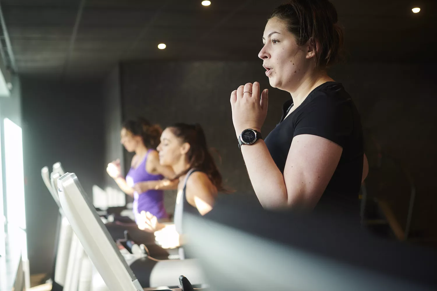 Several women utilizing cardio machines at a fitness center, highlighting a group fitness environment.