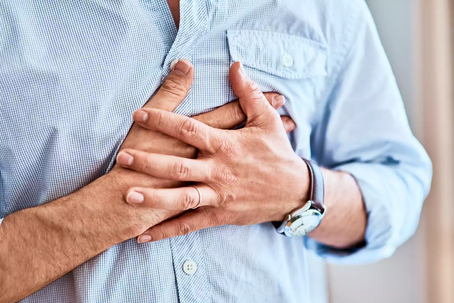 A person holding their chest in discomfort due to the burning sensation of acid reflux.