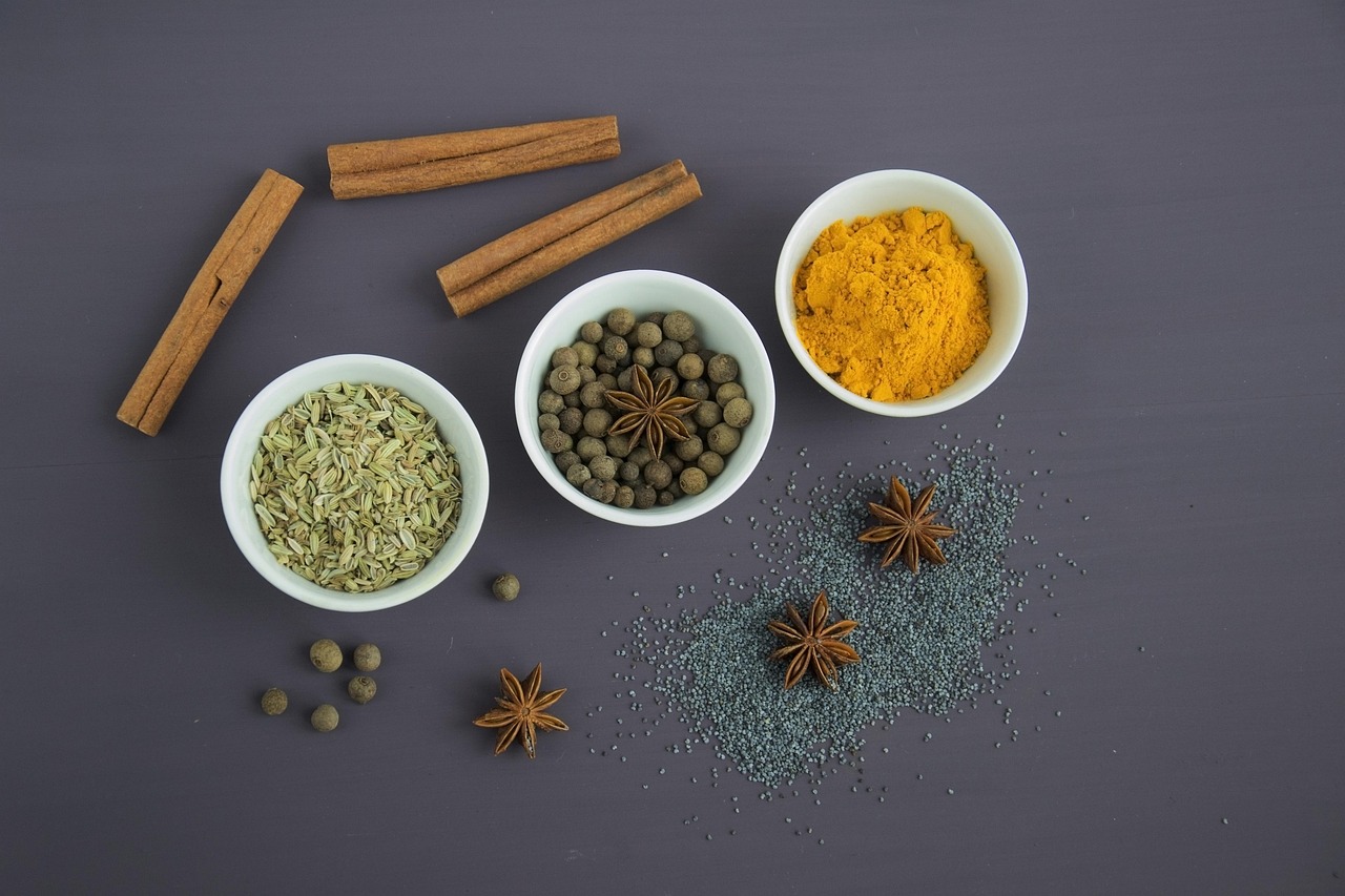 Black peppercorns next to fresh turmeric root