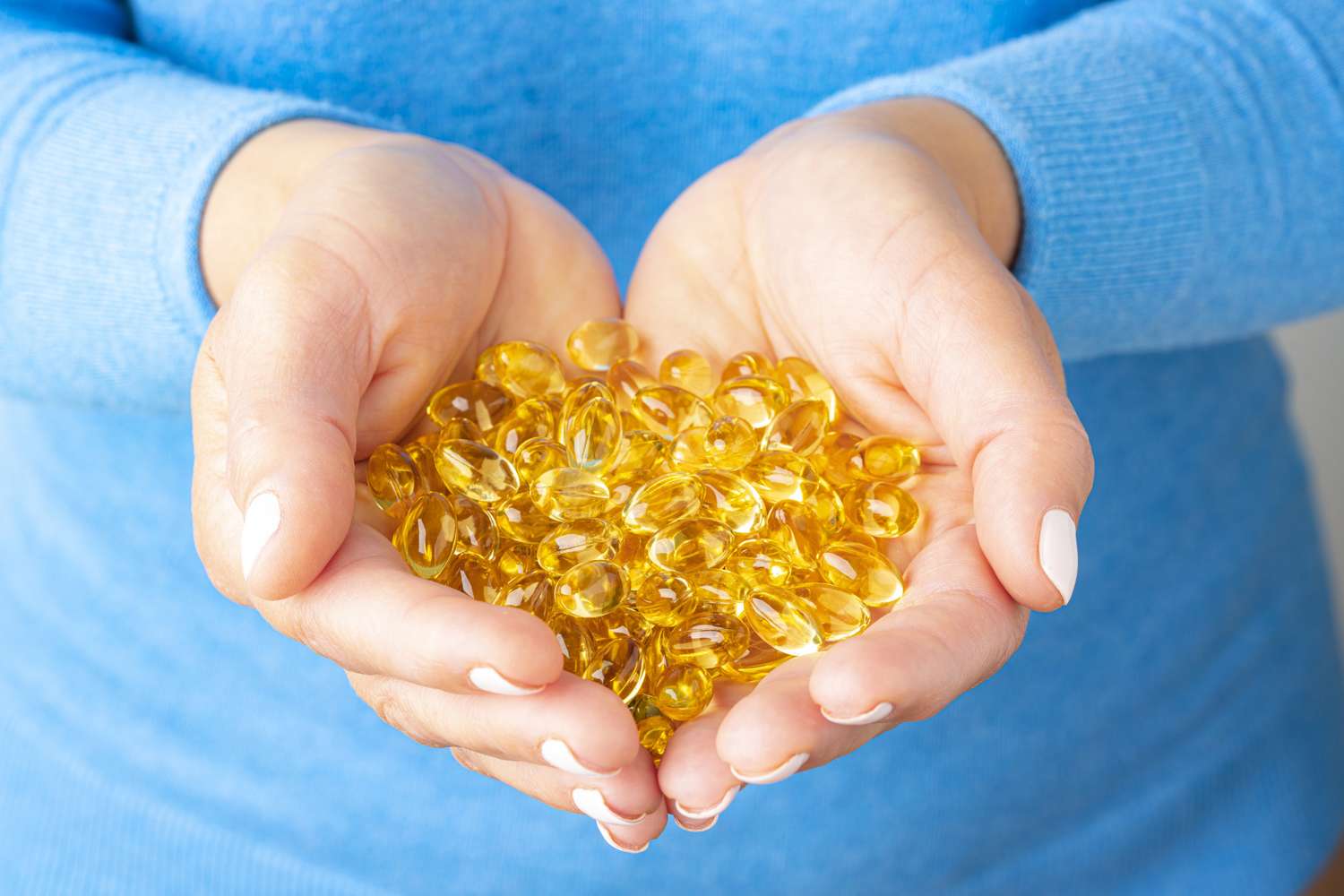 Close-up of translucent vitamin D gel capsules held in a hand.