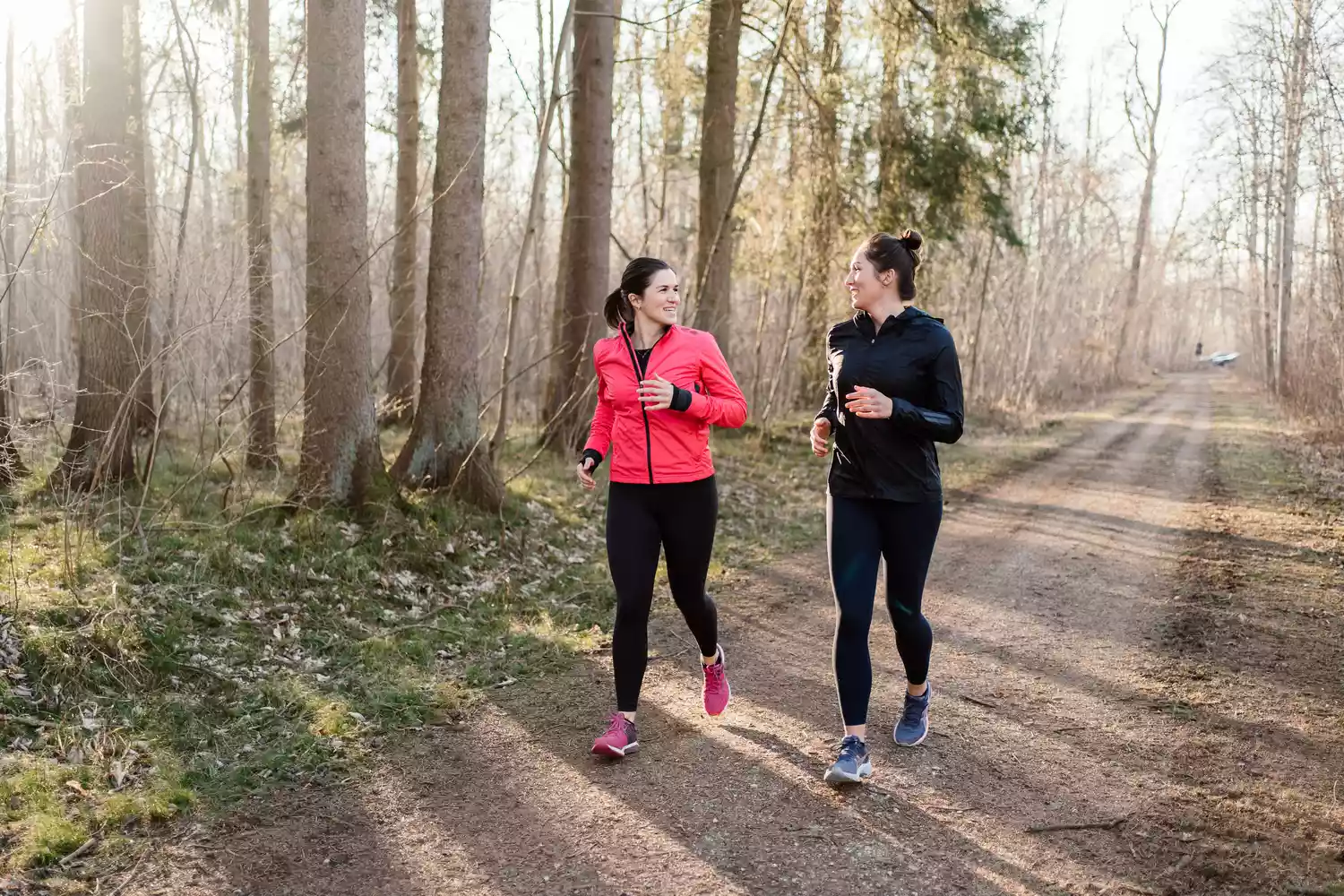 Two senior women jogging together outdoors on a sunny day, showcasing active aging.