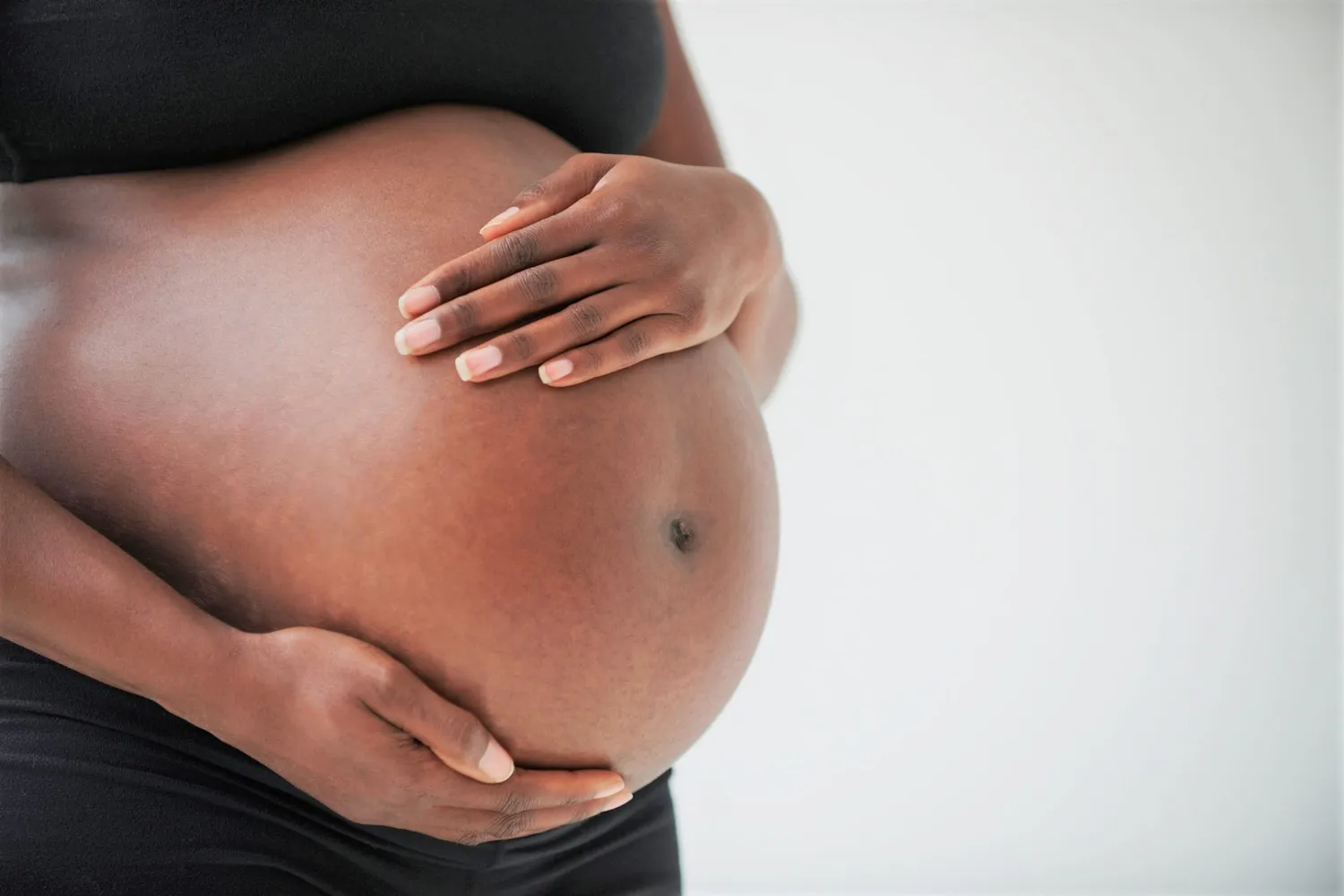 A pregnant woman cradling her belly, symbolizing proactive healthcare and wellness monitoring.