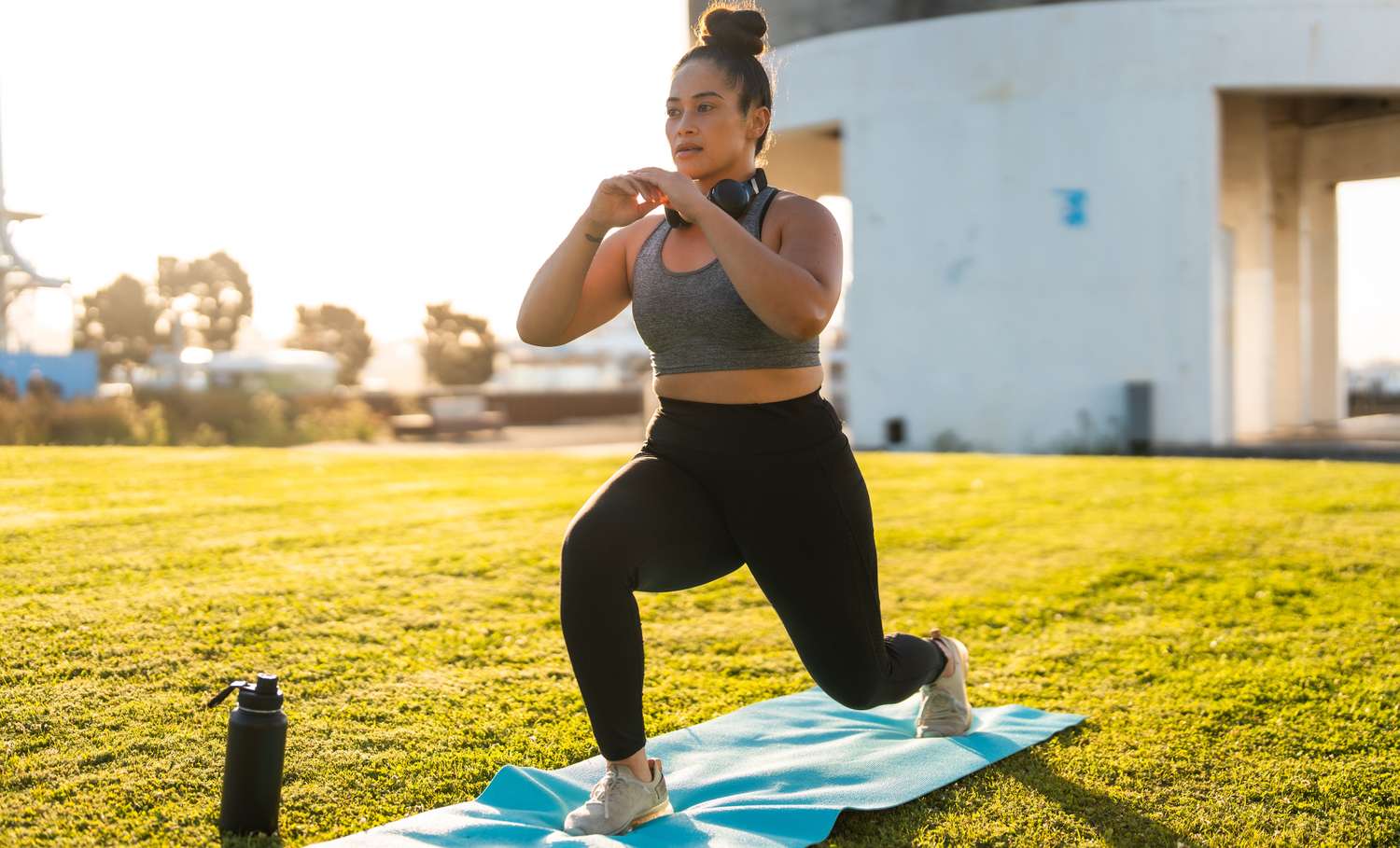A person performing lunges on a yoga mat outdoors to build functional strength.