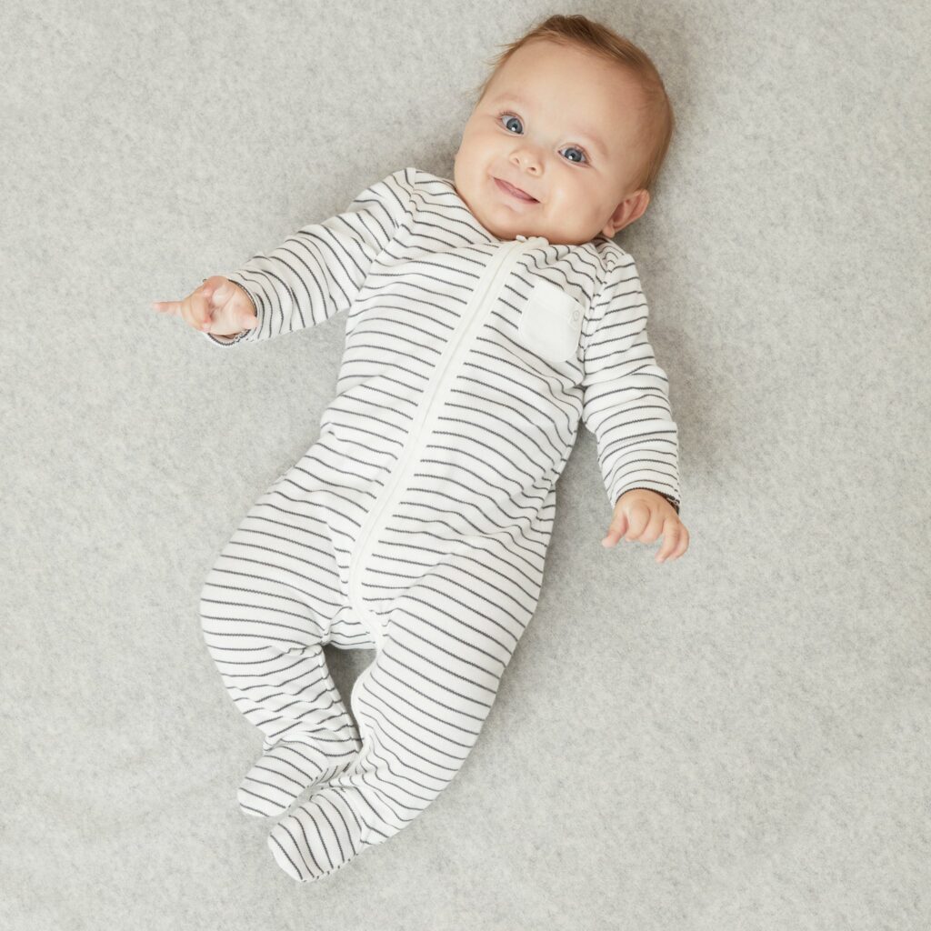 A collection of organic cotton baby sleepsuits and swaddles.