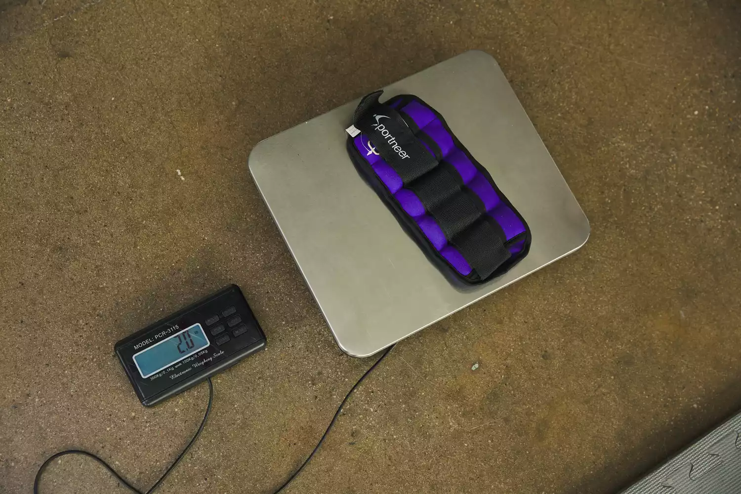 A purple Sportneer ankle weight placed on a digital scale displaying 2.0 lbs.