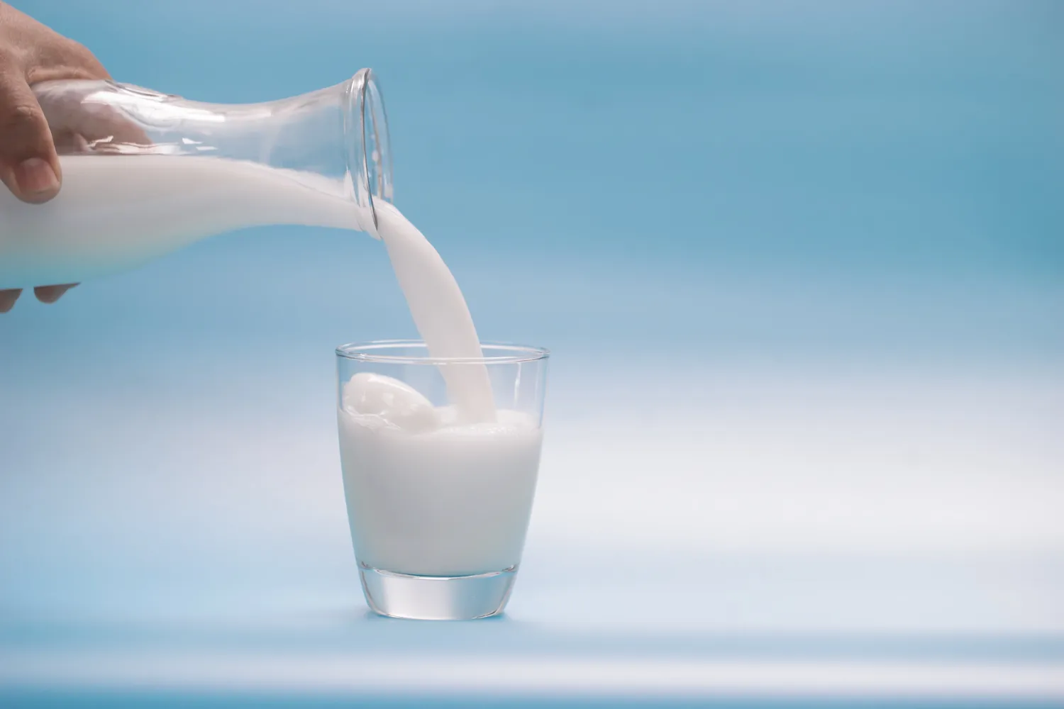 A glass of fresh milk on a blue background.
