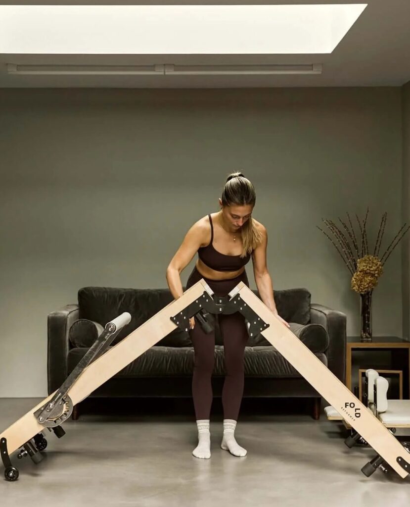 A high-end foldable pilates reformer folded and stored efficiently in a minimalist urban apartment.