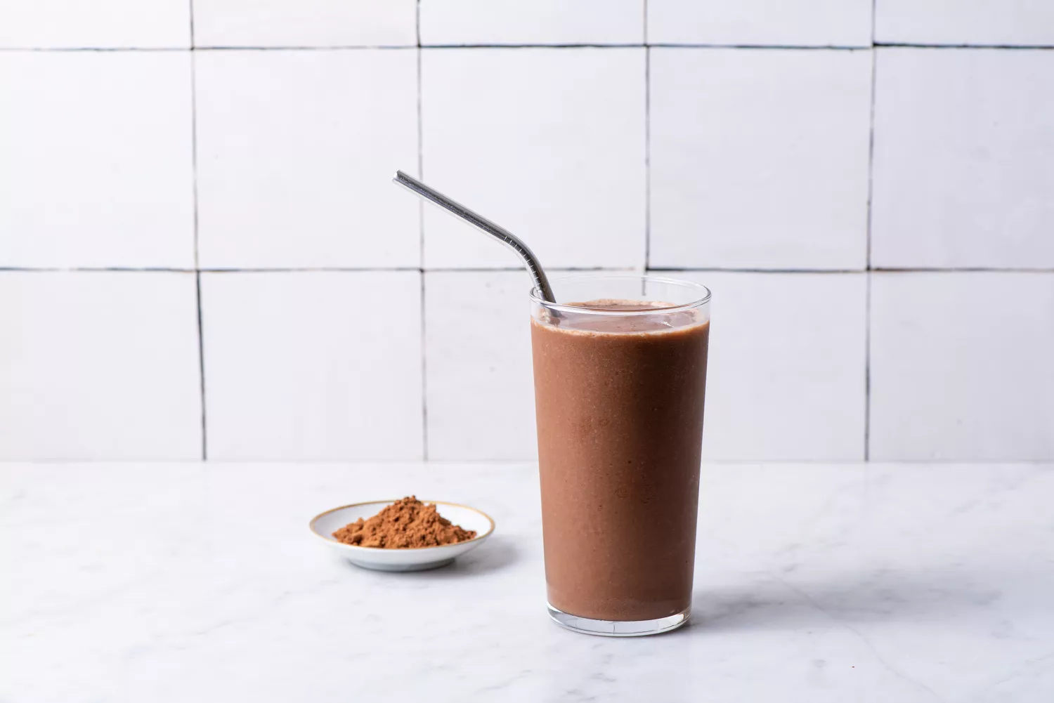 A smooth chocolate-colored protein beverage in a clear glass.