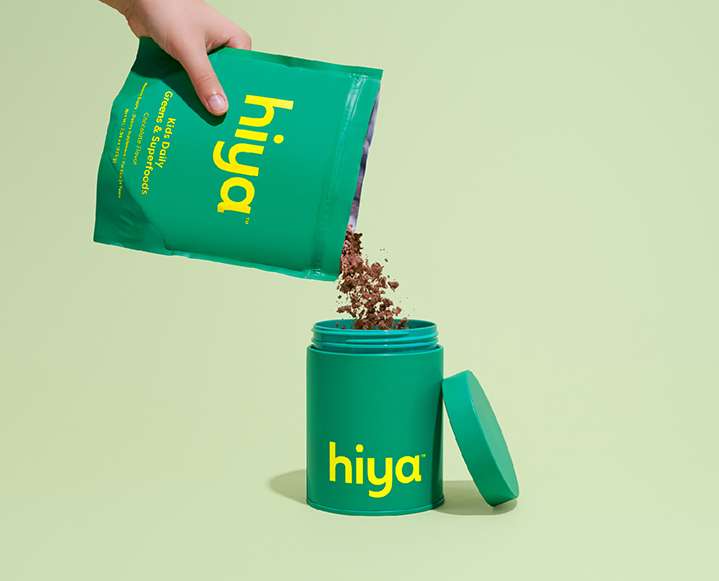 A glass of chocolate milk made with Hiya superfood powder next to a breakfast bowl.
