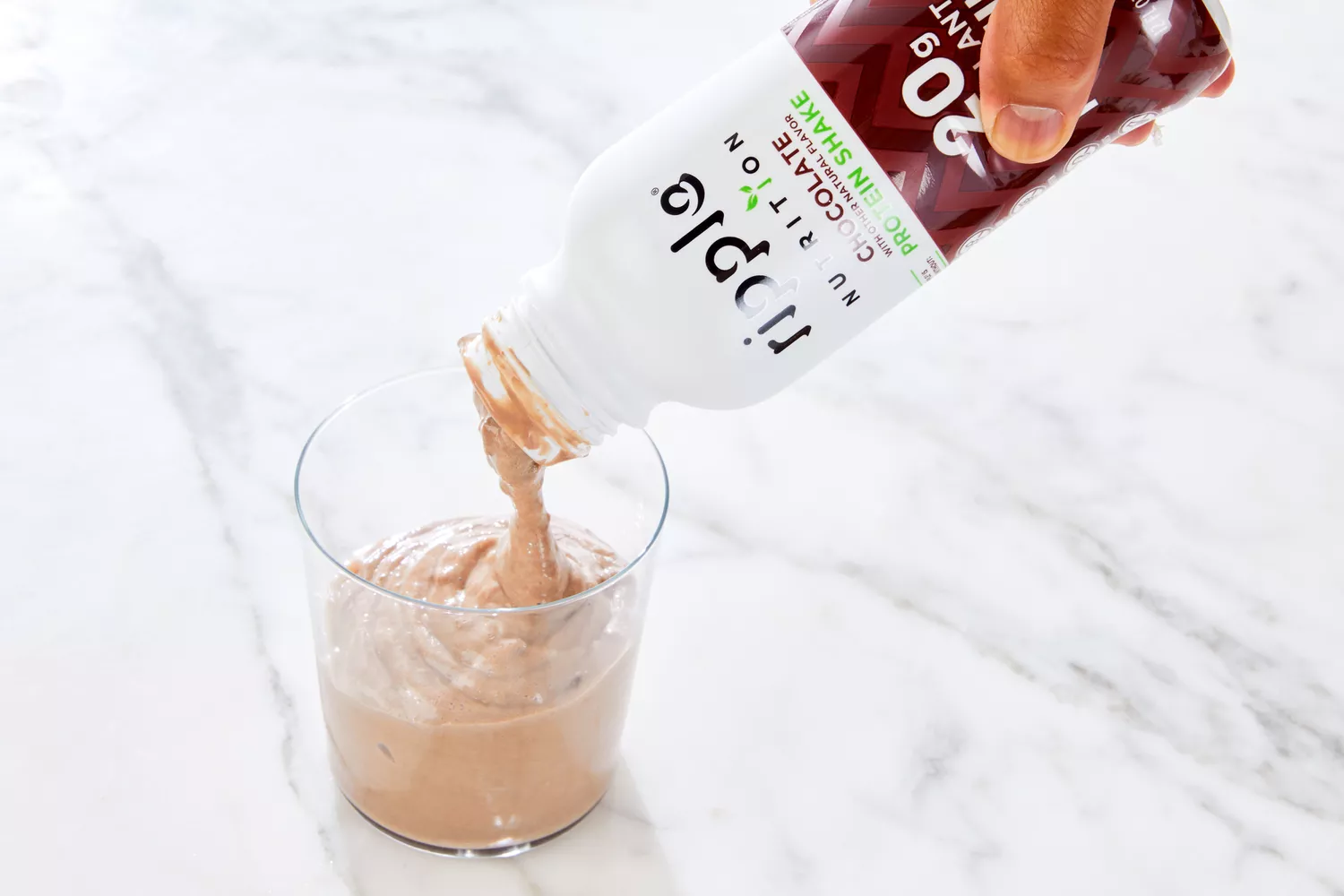 A chocolate-flavored Ripple plant-based protein shake being poured into a glass.