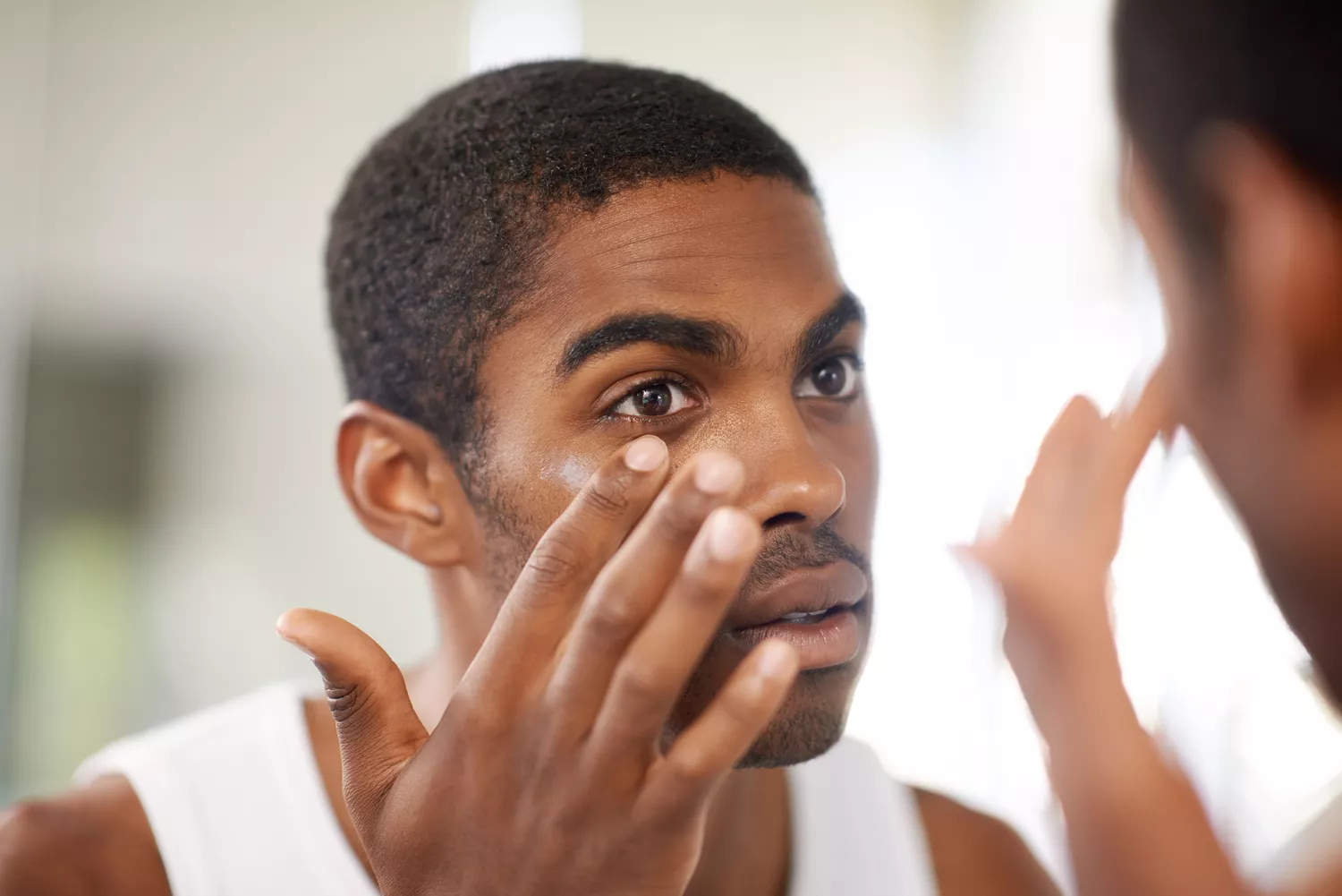 A person looking in the mirror to examine their eye for symptoms