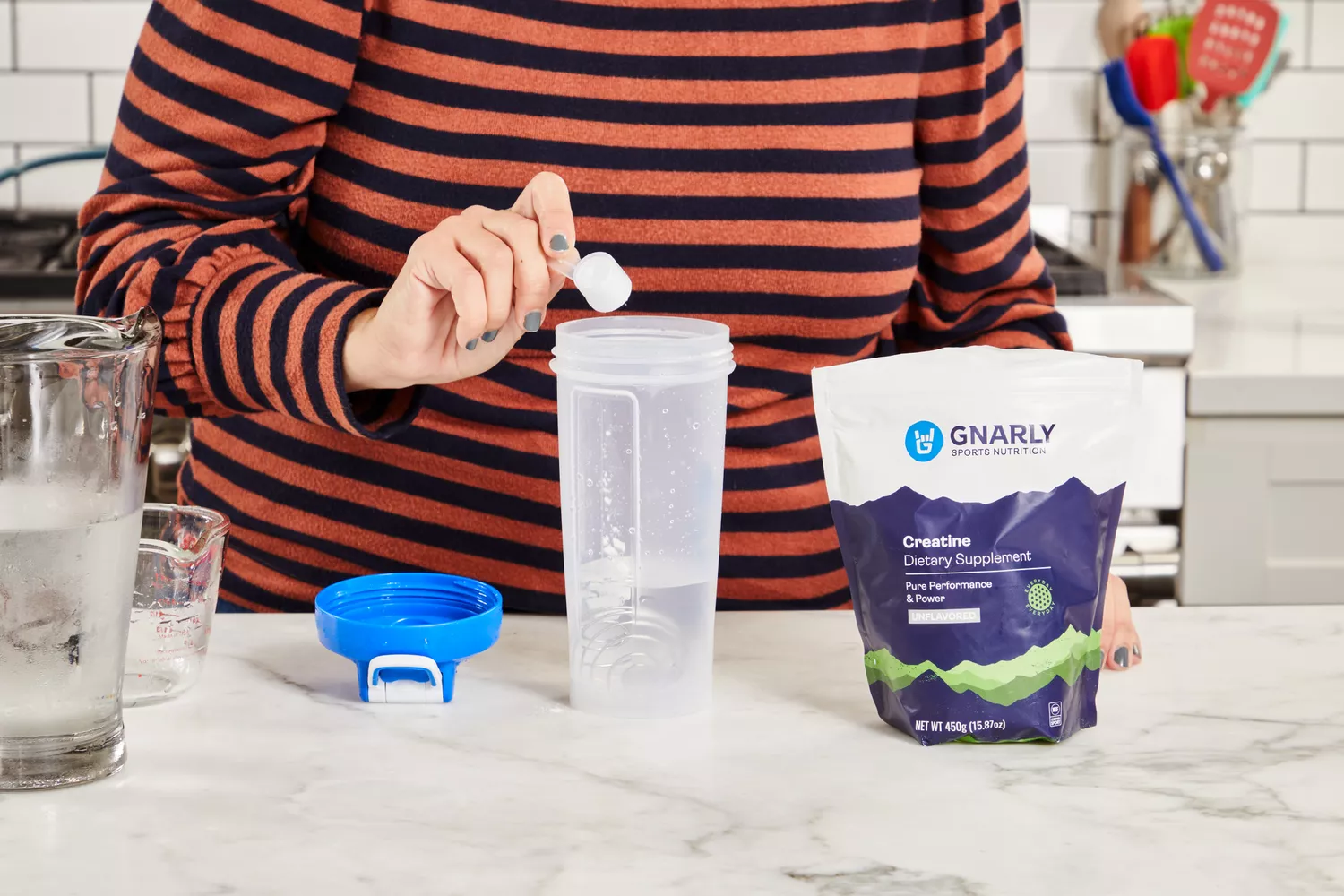 A person adding Gnarly Sports Nutrition Creatine powder to a shaker bottle with water.