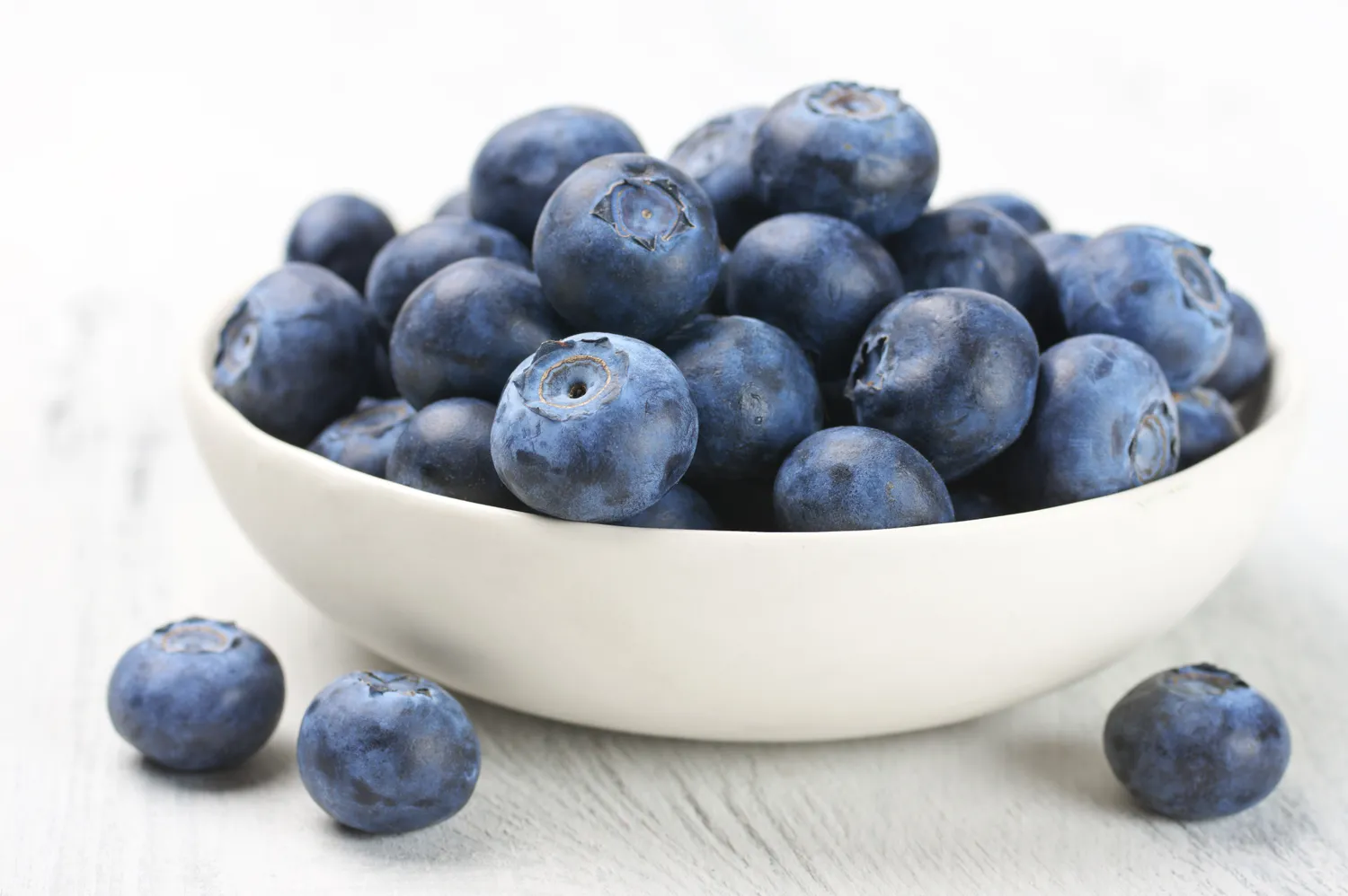 Close-up of fresh blueberries in a white bowl.