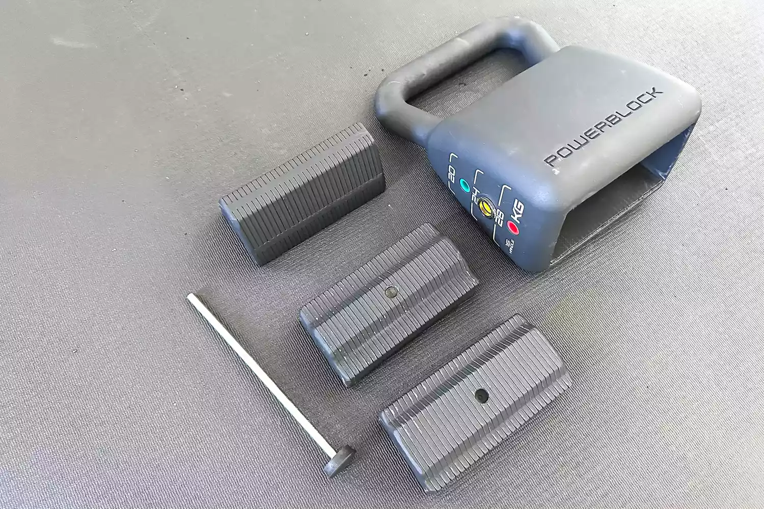 A disassembled PowerBlock adjustable kettlebell showing internal plates and the locking pin.