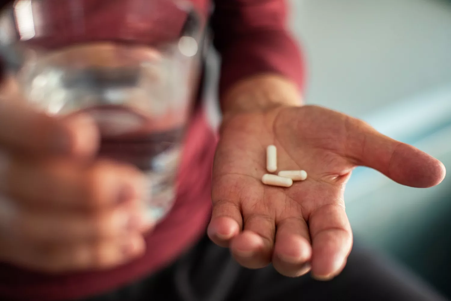 A person taking stimulant laxative capsules with a glass of water.