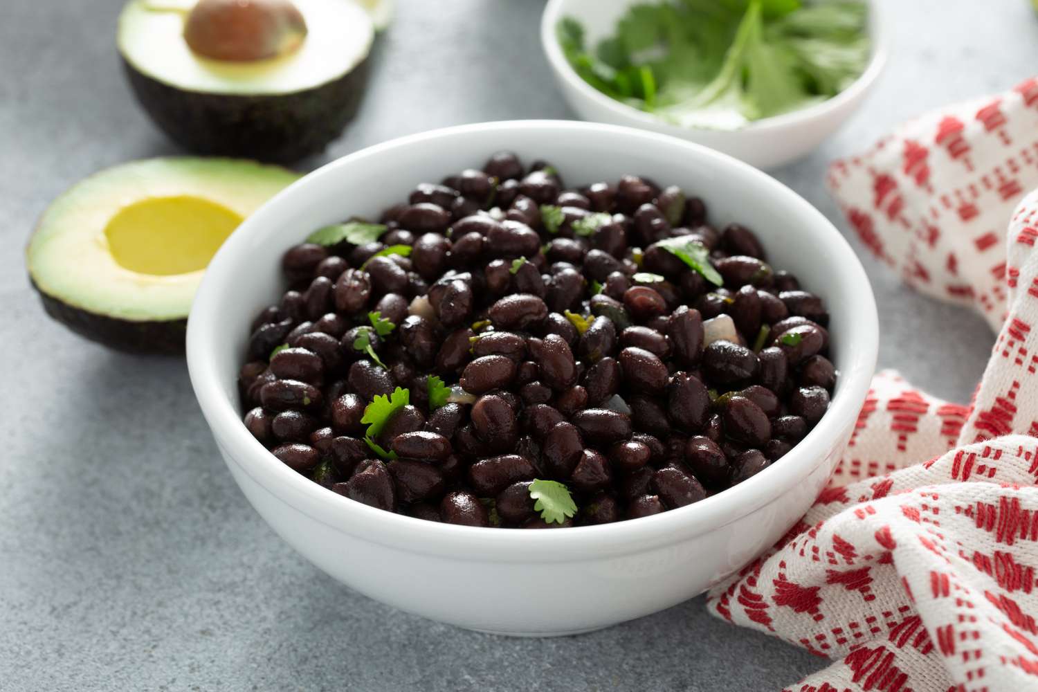 A close-up view of a bowl of black beans garnished with fresh cilantro.